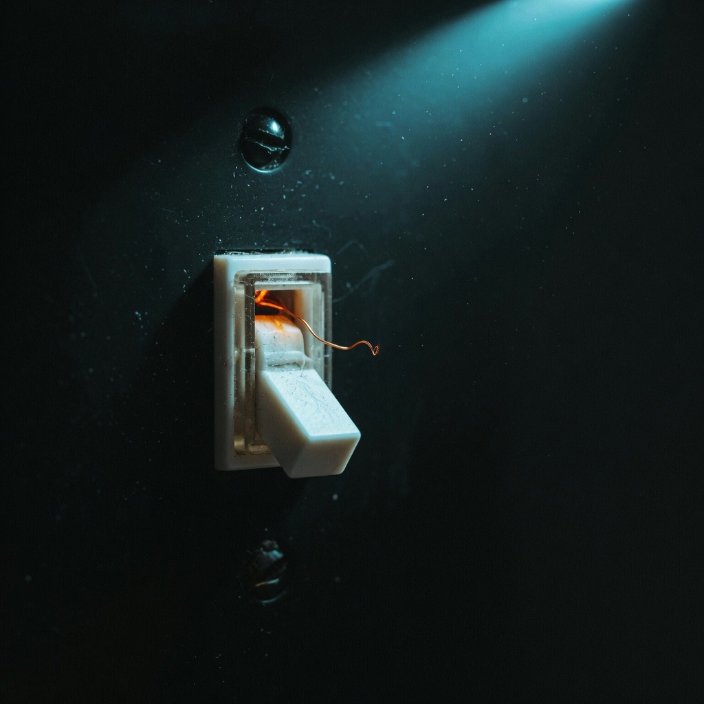 A wall switch in the off position, its filament a dying ember