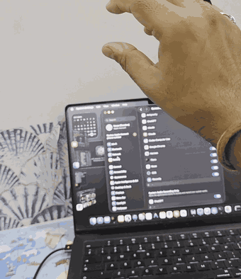 Filmed on a phone: a hand in the air double-pinches and a Finder folder opens, then thumb touches ring finger and the Finder list scrolls